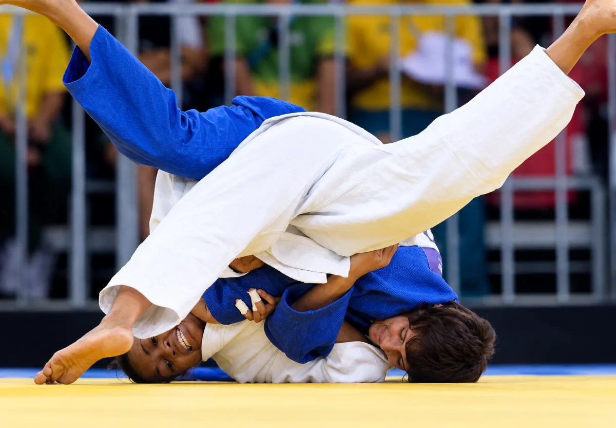 Judo match on a yellow mat: a judoka in blue and one in white mid-throw, Youth Olympic Games, Singapore 2010